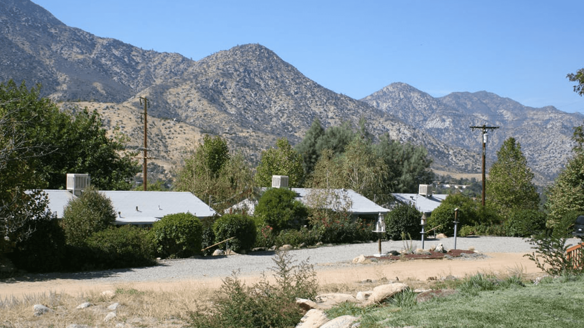 A scenic view of a residential area nestled among rolling mountains under a clear blue sky.